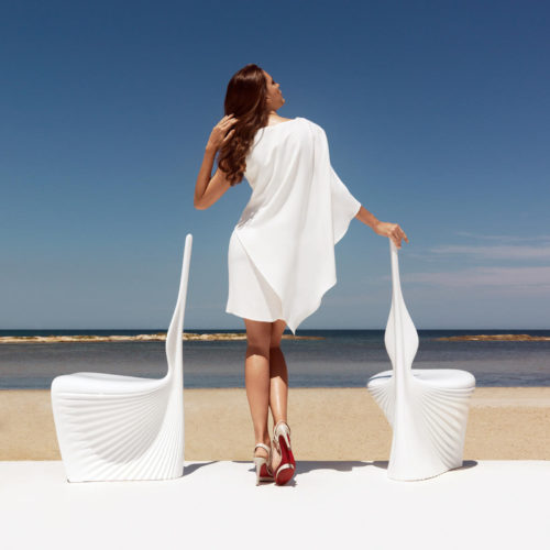 A woman with two white Biophilia dining chairs by Vondom.