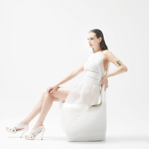 A woman posing on a white biophilia dining chair by Vondom.