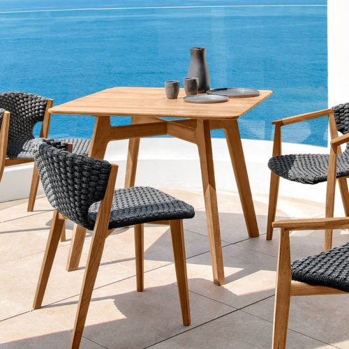 Ethimo's Knit range small dining table with dining chairs by the sea.